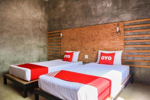 two beds in a room with red and white pillows at OYO 674 Greenery Home in Ranong