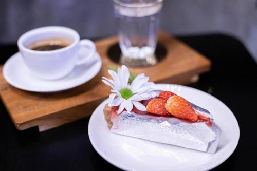 a piece of cake with strawberries and a cup of coffee at The Singha Hotel - Korat in Nakhon Ratchasima