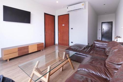 a living room with a leather couch and a glass table at The Singha Hotel - Korat in Nakhon Ratchasima