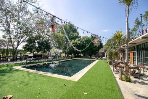 a swimming pool in a park with green grass at OYO 75374 Baan Rak Mai in Kanchanaburi