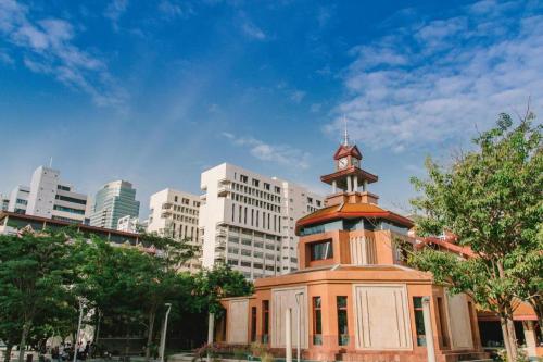 a building with a clock tower in front of a city at Rest@Ratchada hotel in Bangkok
