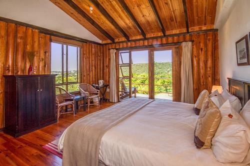 Piesang Valley Lodge في بليتنبيرغ باي: غرفة نوم بسرير كبير وطاولة وكراسي