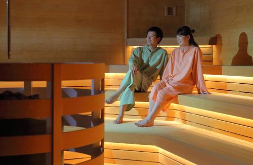 a man and a woman sitting on beds at Yuuyu No Sato Yusa in Yamagata