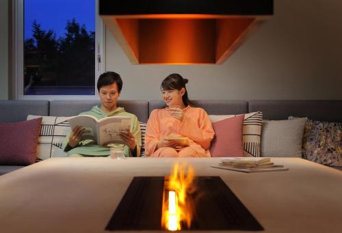 a man and woman sitting on a couch reading books at Yuuyu No Sato Yusa in Yamagata