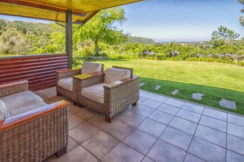 a patio with wicker furniture and a view of a yard at Piesang Valley Lodge in Plettenberg Bay