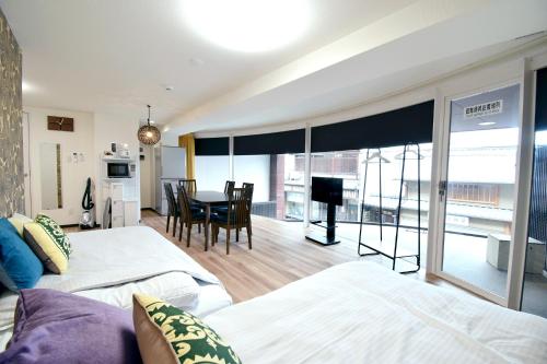 a bedroom with two beds and a dining room with a table at Hostel Inn Kyoto Gion in Giommachi
