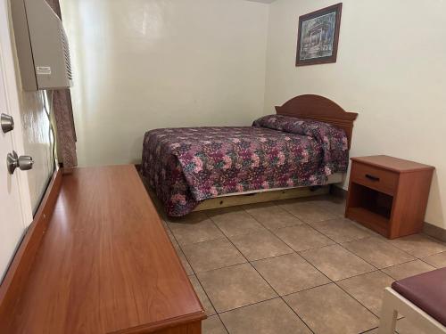 a small bedroom with a bed and a table at Kentucky Motel in Bradenton