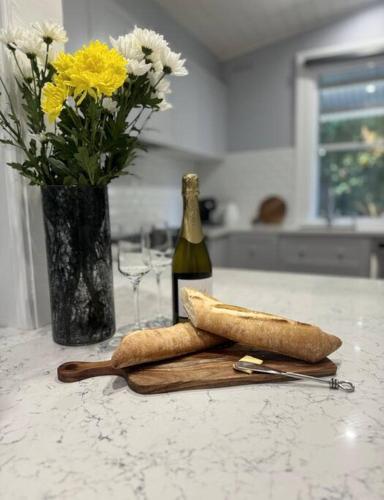 a bottle of wine on a counter with a vase of flowers at The Warra House in Dubbo