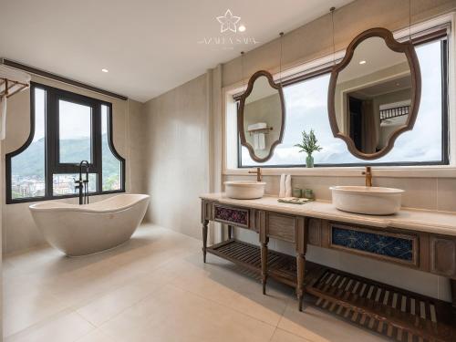 a bathroom with two sinks and a tub and mirrors at Azalea Sapa Hotel in Sa Pa