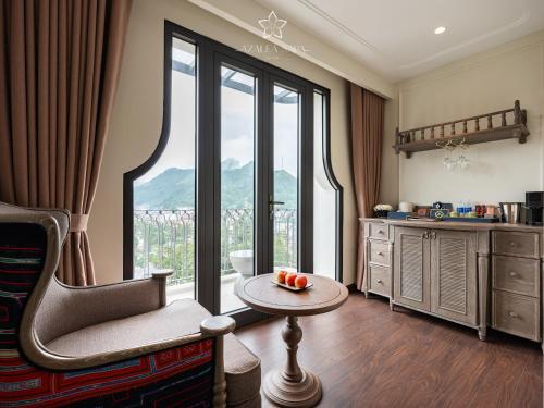 a living room with a chair and a table and a window at Azalea Sapa Hotel in Sa Pa