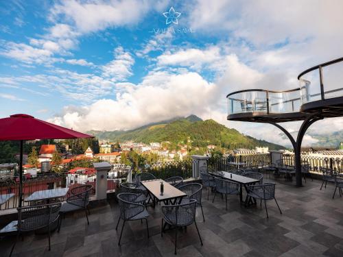 a patio with tables and chairs and a view of a mountain at Azalea Sapa Hotel in Sa Pa
