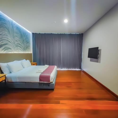 a bedroom with a bed and a flat screen tv at The Riva Vientiane Hotel in Vientiane