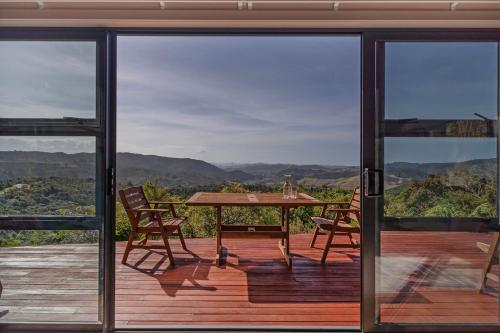 a patio with a table and chairs on a deck at Ridge Valley View in Whenuakite