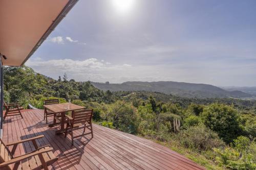 a wooden deck with a table and chairs on it at Ridge Valley View in Whenuakite