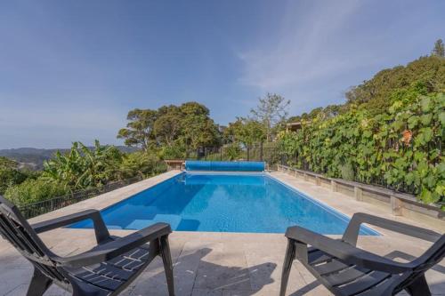 a swimming pool with two chairs sitting next to it at Ridge Valley View in Whenuakite