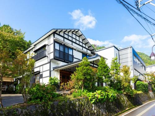 a white building with black windows on a street at Otowaya Ryokan in Yuzawa