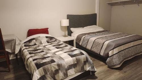 a bedroom with two beds and a table with a lamp at Tom oker in Mississauga
