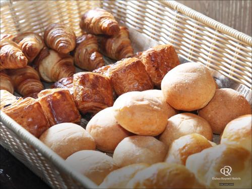 a basket full of different types of bread and pastries at Daiwa Roynet Hotel Matsuyama in Matsuyama