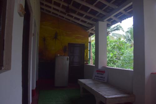 a porch with a wooden bench and a window at Castellos tourist nest in Benaulim