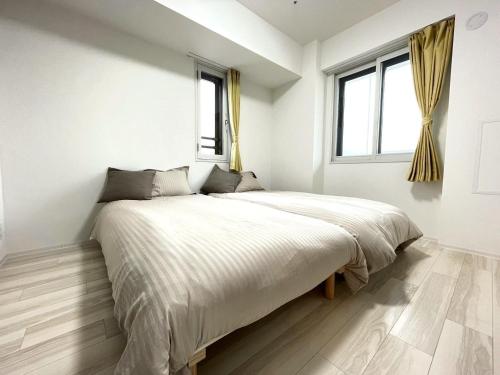 a bedroom with a large bed in a room with windows at 902 6名様宿泊可能 札幌中心部 すすきの駅より徒歩5分 ロケーション最高 in Sapporo