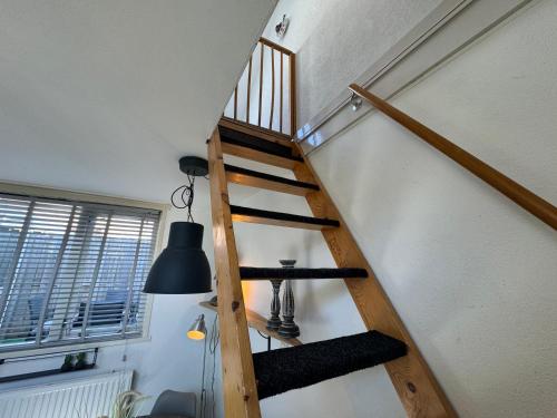 a wooden staircase in a room with a black lamp at Vakantiehuisje aan Zee - 100m van Strand in Egmond aan Zee