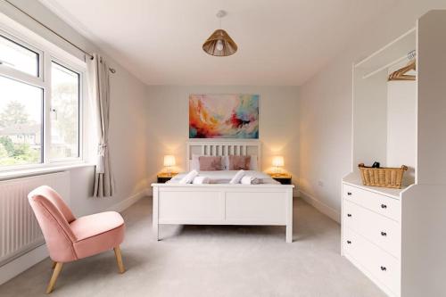 a bedroom with a white bed and a pink chair at Beechwood House in Melton Mowbray