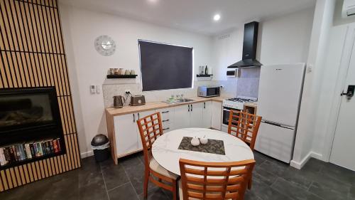 a kitchen with a table and chairs and a refrigerator at Sauvage - Luxury Garden Apartment in Port Pirie