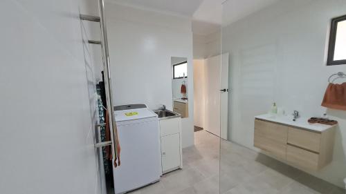 a white kitchen with a sink and a refrigerator at Sauvage - Luxury Garden Apartment in Port Pirie