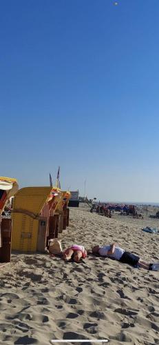 two people laying on the sand on the beach at Vakantiehuisje aan Zee - 100m van Strand in Egmond aan Zee