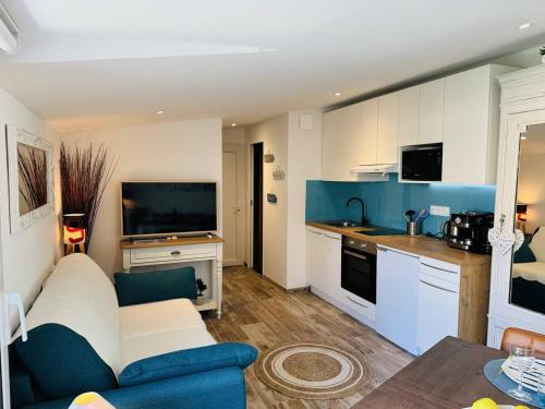 un salon avec un canapé bleu et une cuisine dans l'établissement Studio Ty Cool, jardin 200m carré, 50m plage, wifi, parking, à Penthièvre