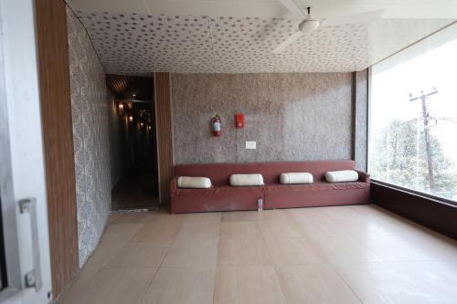 a red couch in a room with a large window at Sleeping Beauty Hotel Moutain view property in Joshīmath