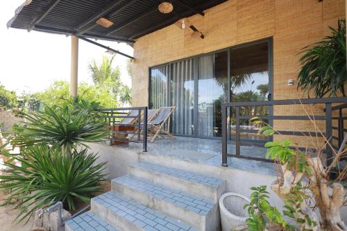 a house with stairs and a patio with a table at Hành Ngò Homestay - Hòn Đỏ Ninh Thuận in Thôn Dư Khánh