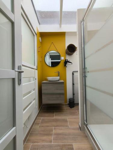 La salle de bains est pourvue d'un lavabo et d'un mur jaune. dans l'établissement Le Cosy du Centre - Proche plage et Port, à Grand-Fort-Philippe
