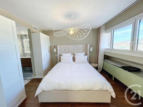 - une chambre avec un grand lit blanc et un lustre dans l'établissement Vue mer exceptionnelle - Appartement Deluxe, à Cannes