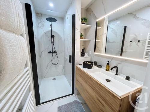 La salle de bains est pourvue d'une douche et d'un lavabo blanc. dans l'établissement Vue mer exceptionnelle - Appartement Deluxe, à Cannes
