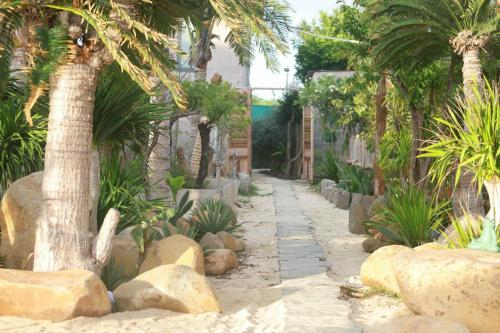 a garden with palm trees and rocks and a sidewalk at Hành Ngò Homestay - Hòn Đỏ Ninh Thuận in Thôn Dư Khánh