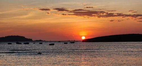 a sunset over the ocean with boats in the water at Hành Ngò Homestay - Hòn Đỏ Ninh Thuận in Thôn Dư Khánh