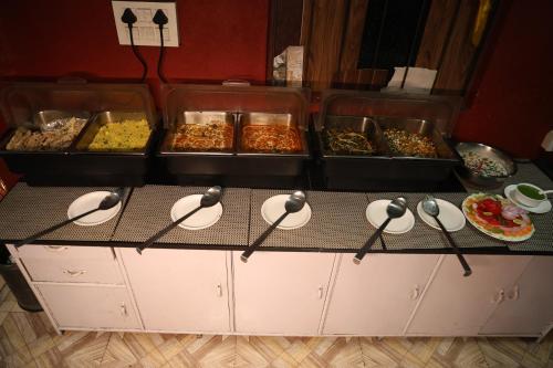 a buffet with several trays of food on a counter at Sleeping Beauty Hotel Moutain view property in Joshīmath