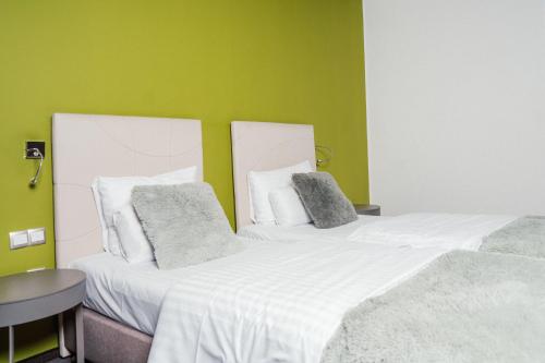 two beds in a room with green walls at Hotel City Maribor in Maribor