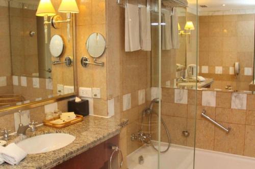 a bathroom with a shower and a sink and a tub at Kai Wah Plaza International Hotel in Kunming