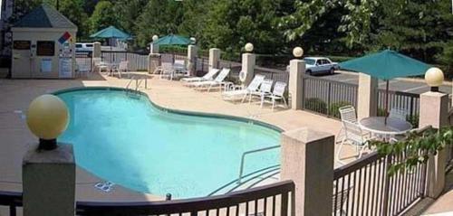 a large swimming pool with chairs and tables and umbrellas at Sleep Inn Airport - Billy Graham Parkway in Charlotte