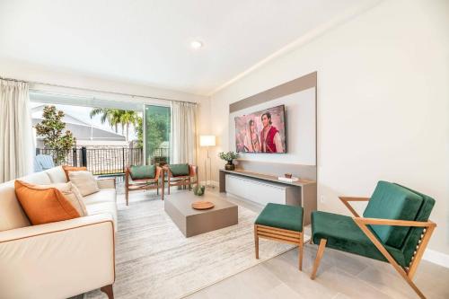 a living room with a white couch and green chairs at 7992 Cozy 5BD Disney Getaway with Pool in Orlando