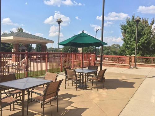a patio with tables and chairs and a green umbrella at The Q Hotel & Suites in Springfield