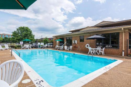 a swimming pool with white chairs and tables at Quality Inn in Manassas