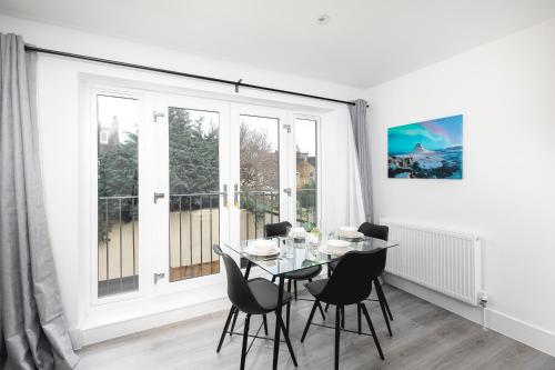 ein Esszimmer mit Tisch und Stühlen und einem großen Fenster in der Unterkunft CoZy Apartments With King Size Beds Near Enfield Town & Chase Farm Train Stations With Wifi and Parking in Enfield