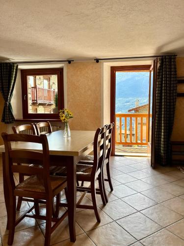 a dining room with a table and chairs and a balcony at Maison Arcade in Challancin