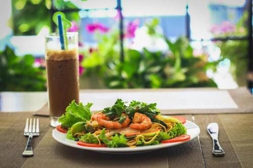 a plate of food on a table with a drink at Vientiane Chaleunxay Center Hotel in Vientiane