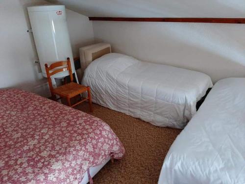 une petite chambre avec deux lits et une chaise dans l'établissement Appart piau résidence le village, à Aragnouet