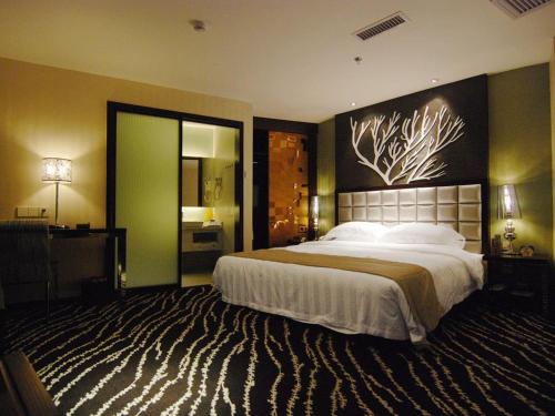 a bedroom with a large bed with a painting on the wall at Kunming Long Way Hotel in Kunming