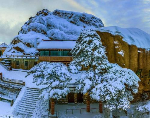 a building covered in snow next to a mountain at Huangshan Yupinglou Hotel in Huangshan